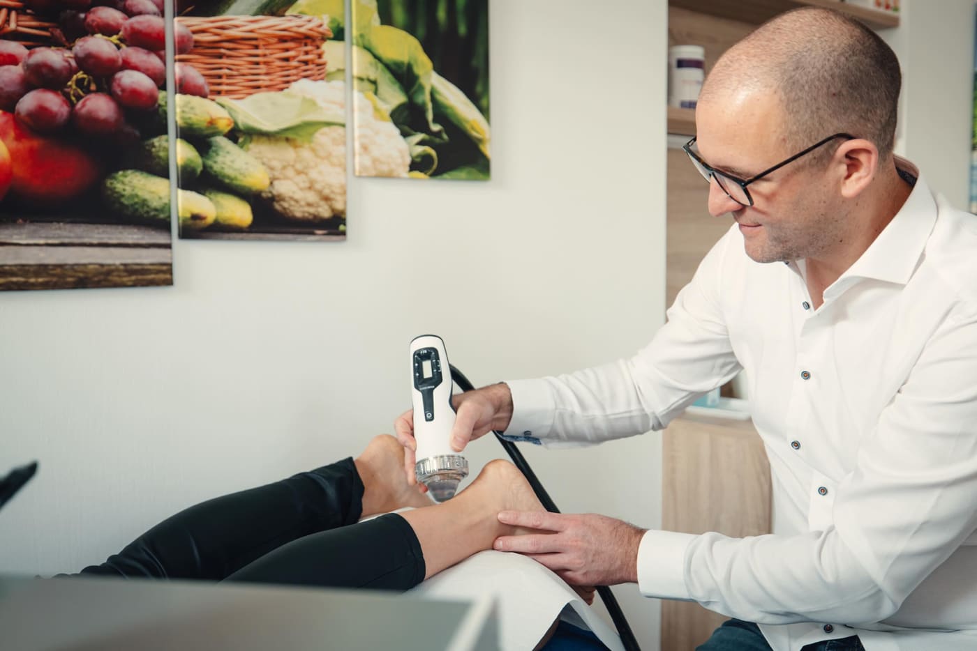 Dr. Thomas Laimer behandelt die Ferse einer Patientin mit Stoßwellentherapie
